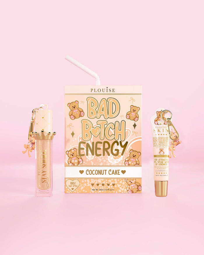 Un P.Louise Teddy Glitter Bad Bitch Energy Lip Duo cu parfum de tort de cocos, cu un balsam de buze și ulei de buze pe un fundal roz