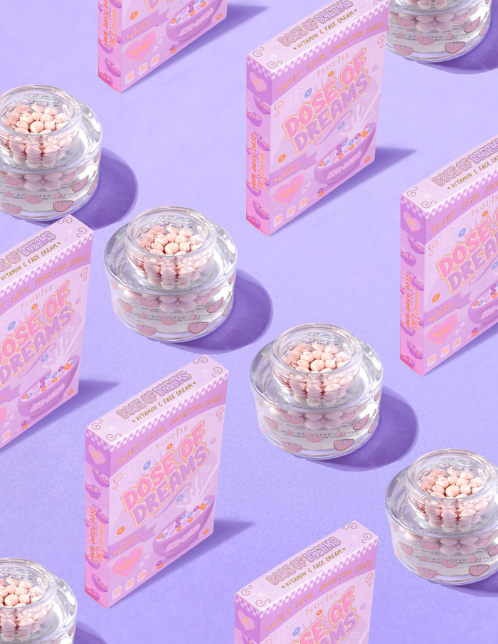 Recipiente transparente de P.Louise DOse of Dreams Viatmin C Capsule Cremă de față cu capsulă roz în ele înconjurate de cutii de cereale roz pe un fundal violet