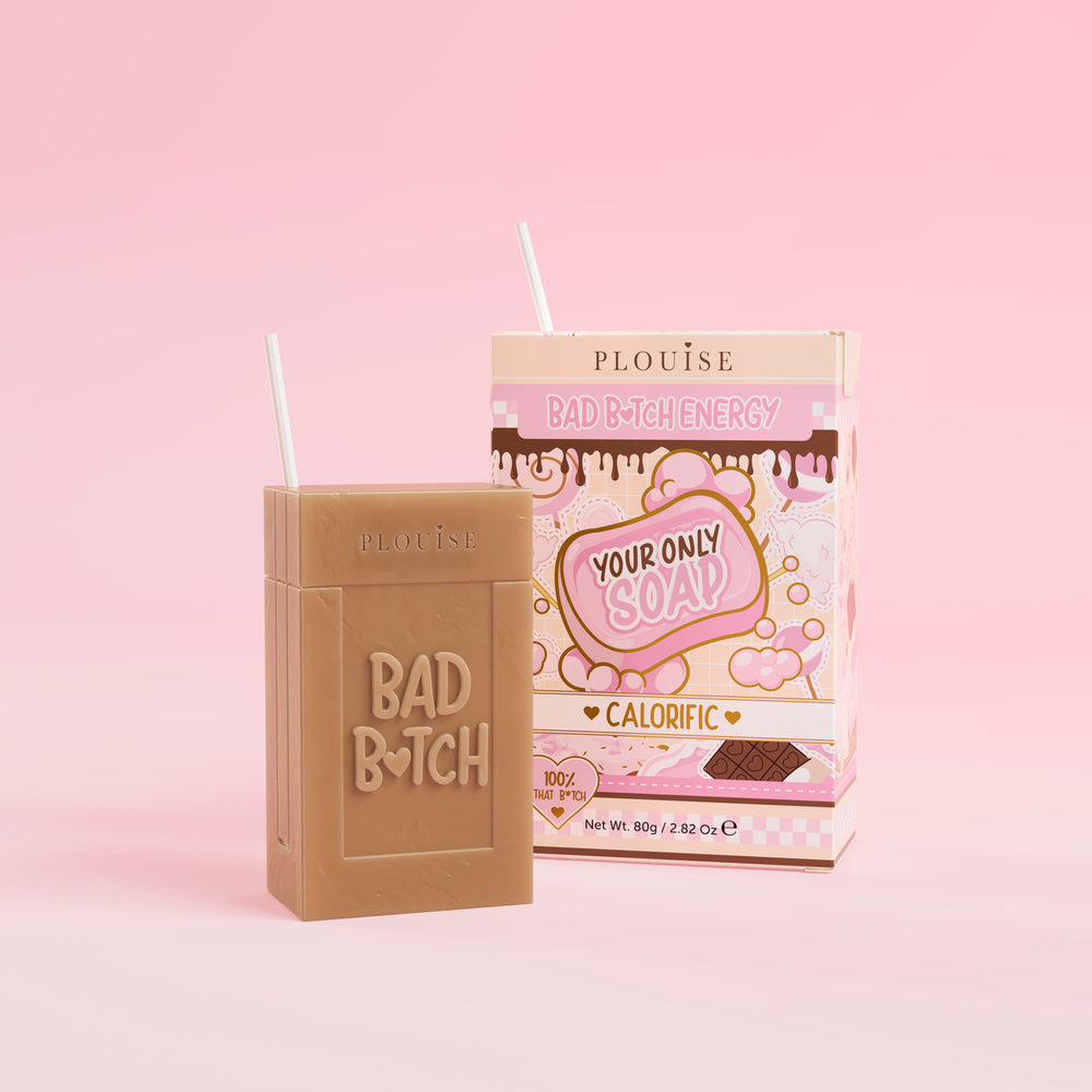 A brown bar of soap with 'Bad Bitch' engraved on it, accompanied by a colourful juice box package with 'Calorific' labelled on it, presented on a pink background.