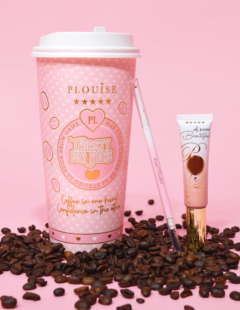 O imagine de produs care prezintă un creion pentru sprâncene cu două capete lângă un tub de gel pentru sprâncene, afișat pe o suprafață roz cu boabe de cafea împrăștiate. Fundalul are o ceașcă de cafea roz cu elemente de branding.