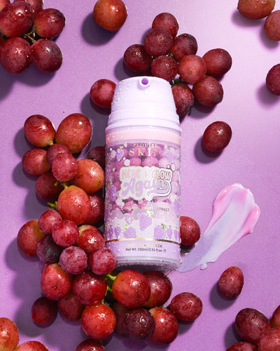 Sticlă violet de P. Louise Here I Glow Again Grape Recovery Mask înconjurată de struguri pe un fundal violet