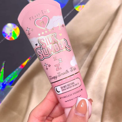 O persoană care ține în mână un tub de P.Louise Silk Slumber Poreless Primer cu un fundal roz și detalii despre produse cosmetice.
